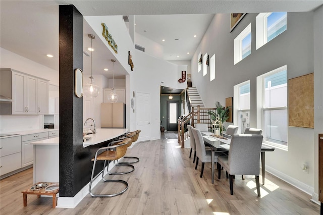 dining space featuring visible vents, light wood-style flooring, stairway, and plenty of natural light