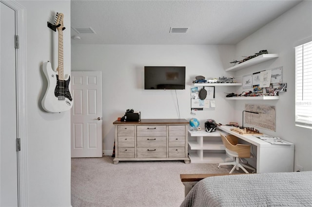 bedroom featuring built in desk, a textured ceiling, carpet, and visible vents
