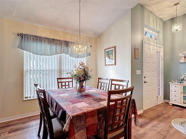 dining area with baseboards, wood finished floors, and a notable chandelier