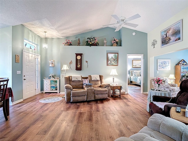 living room with high vaulted ceiling, wood finished floors, a textured ceiling, baseboards, and ceiling fan