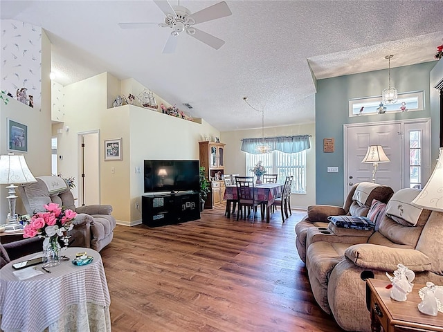 living area featuring high vaulted ceiling, a textured ceiling, baseboards, wood finished floors, and ceiling fan with notable chandelier