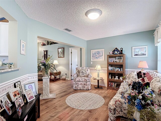 sitting room with baseboards, a textured ceiling, visible vents, and light wood-type flooring