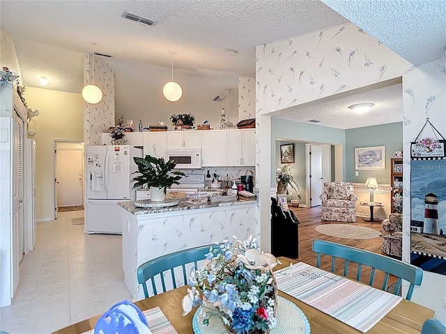 dining area with light tile patterned flooring, a textured ceiling, and visible vents