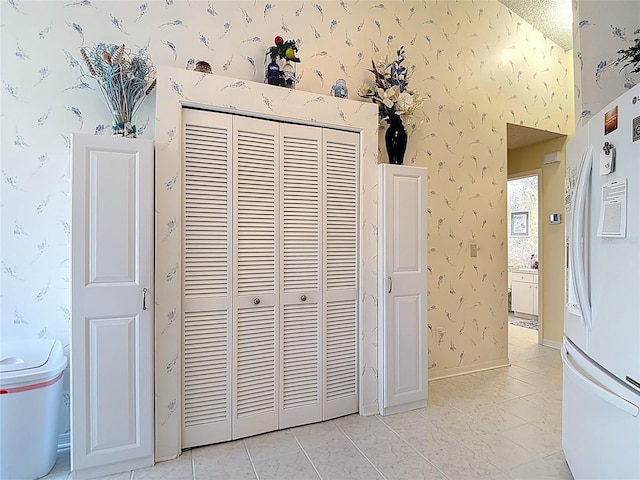 details with baseboards, wallpapered walls, and white refrigerator with ice dispenser