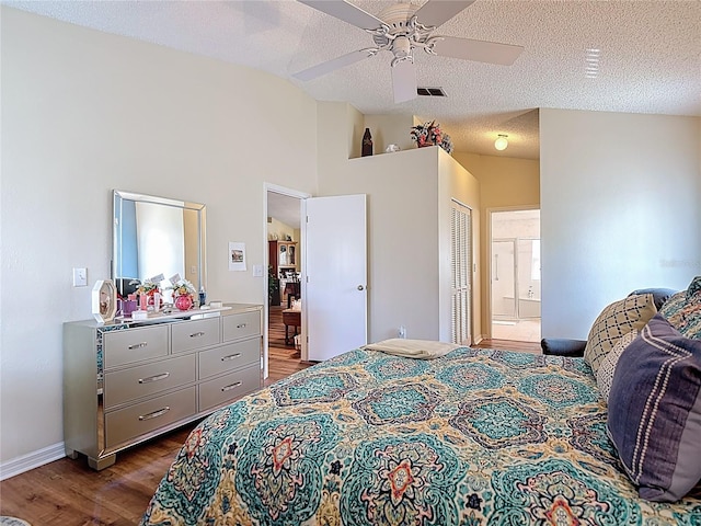 bedroom featuring vaulted ceiling, dark wood-style flooring, a textured ceiling, visible vents, and ensuite bathroom