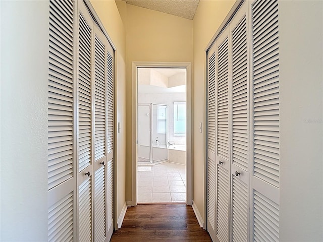 corridor with dark wood finished floors, baseboards, and a textured ceiling