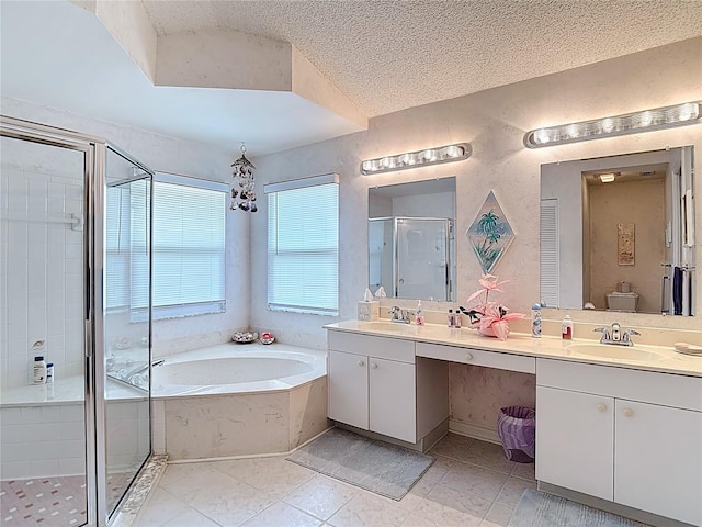 bathroom featuring a bath, a textured ceiling, a shower stall, double vanity, and a sink