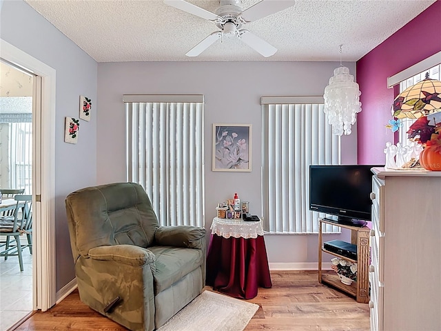living area featuring a textured ceiling, wood finished floors, and ceiling fan