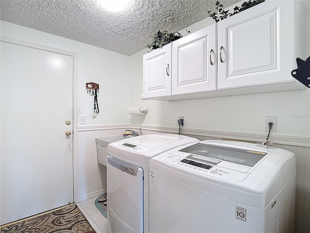 washroom featuring cabinet space, a textured ceiling, a wainscoted wall, and washer and dryer