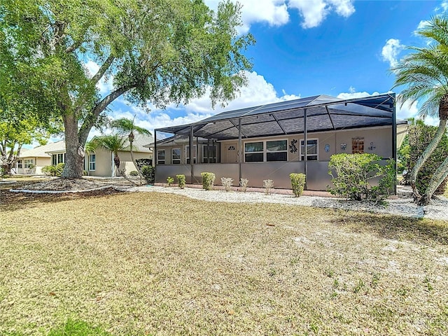 rear view of house featuring glass enclosure, a lawn, and stucco siding