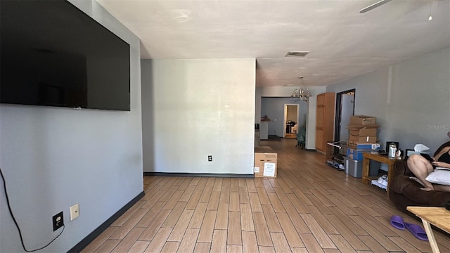 living area with light wood-style flooring, ceiling fan, baseboards, and a chandelier