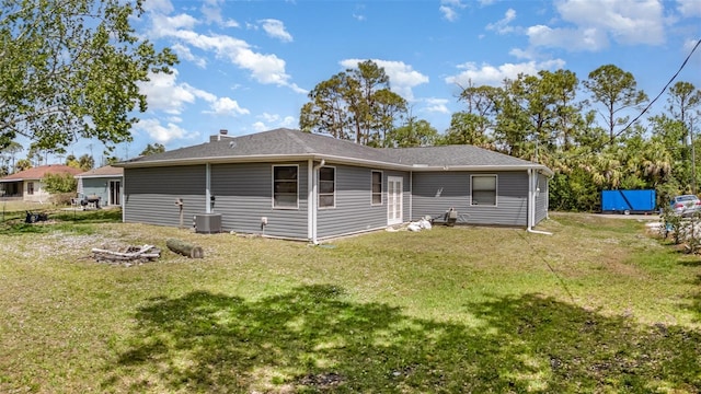 back of house with a lawn, central air condition unit, and a fire pit