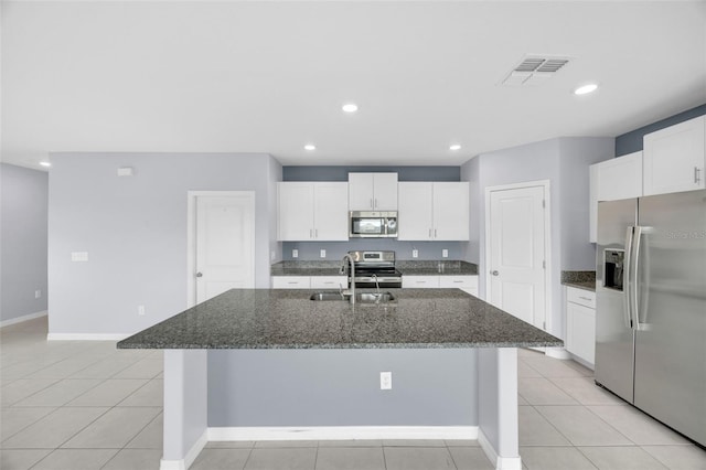 582 Royal Empress Dr, Ruskin, FL 33570 - kitchen with stainless steel appliances, a center island with sink, white cabinetry, dark stone countertops, and recessed lighting