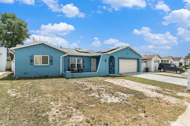 ranch-style home featuring an attached garage, roof mounted solar panels, concrete driveway, and stucco siding