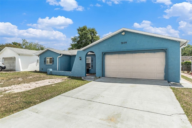 ranch-style house with concrete driveway, stucco siding, and an attached garage