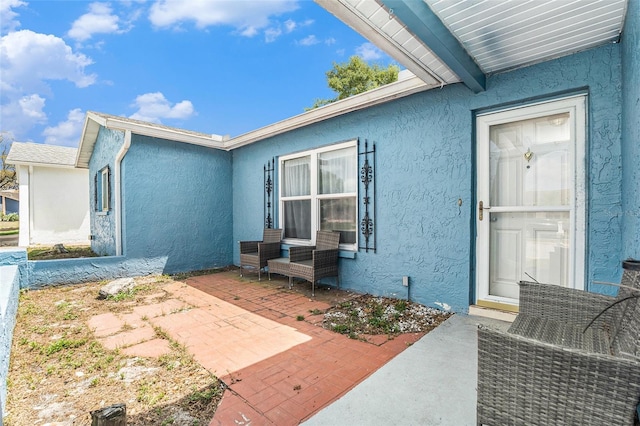 entrance to property with a patio and stucco siding