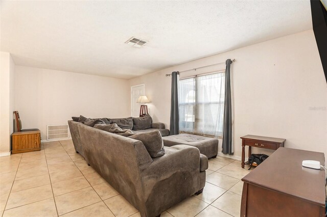 living area featuring light tile patterned floors, visible vents, and a textured ceiling