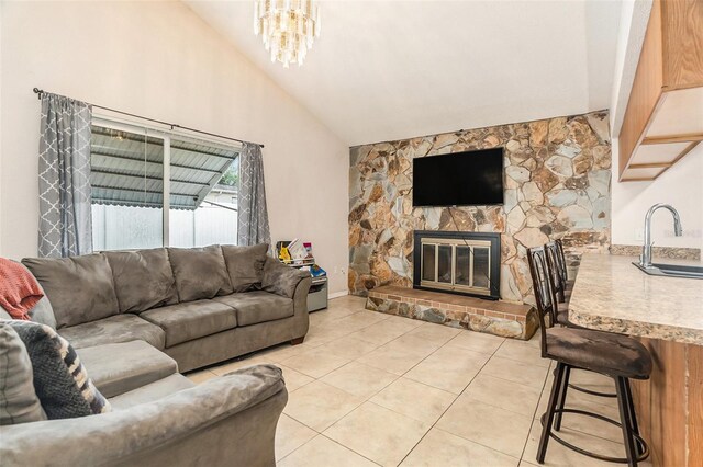 living room with a chandelier, a stone fireplace, high vaulted ceiling, and light tile patterned flooring