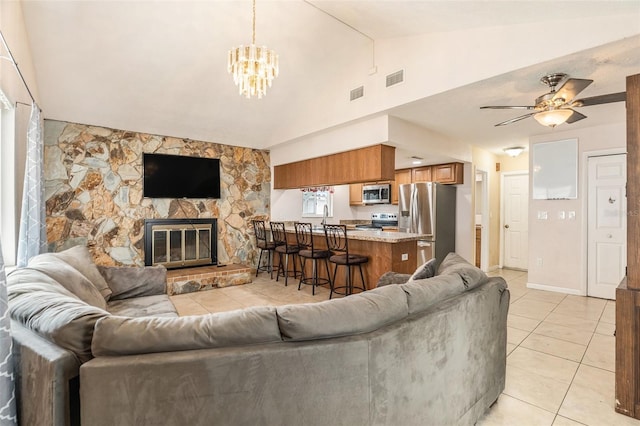 living area featuring light tile patterned flooring, visible vents, a fireplace, and lofted ceiling