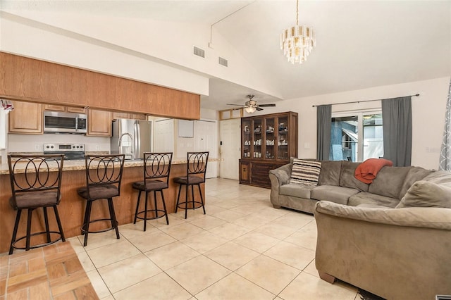 living area with visible vents, high vaulted ceiling, light tile patterned floors, and ceiling fan with notable chandelier