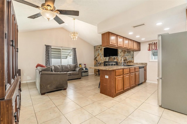 kitchen featuring ceiling fan with notable chandelier, appliances with stainless steel finishes, a sink, lofted ceiling, and open floor plan