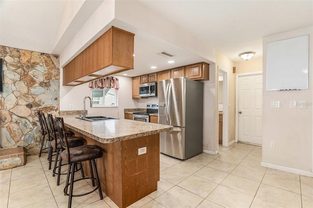 kitchen with a kitchen breakfast bar, a peninsula, visible vents, appliances with stainless steel finishes, and a sink