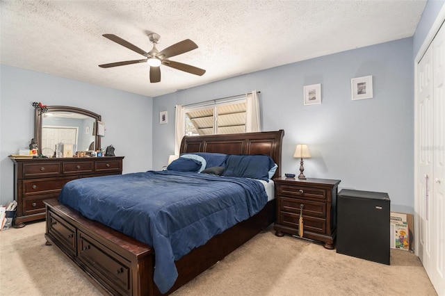 bedroom featuring light carpet, a closet, a textured ceiling, and ceiling fan