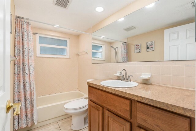 bathroom featuring shower / bath combination with curtain, visible vents, toilet, tile walls, and tile patterned floors
