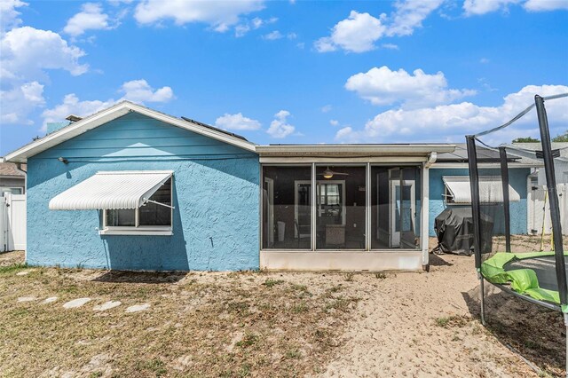 rear view of property featuring a trampoline and stucco siding