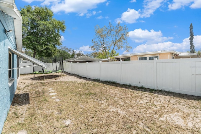 view of yard featuring a trampoline and a fenced backyard