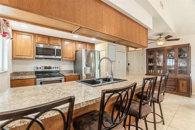 7426 Cay Dr, Port Richey, FL 34668 - kitchen featuring appliances with stainless steel finishes, a sink, a kitchen bar, ceiling fan, and light countertops