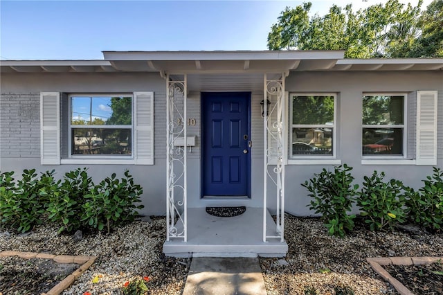 view of exterior entry with brick siding and stucco siding