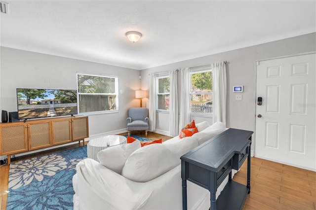 living room featuring visible vents, baseboards, and wood finished floors