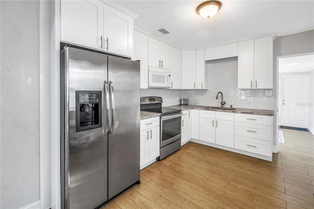 kitchen with light stone counters, light wood-style flooring, visible vents, stainless steel appliances, and a sink