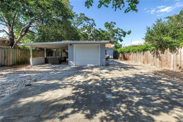 garage featuring concrete driveway and fence