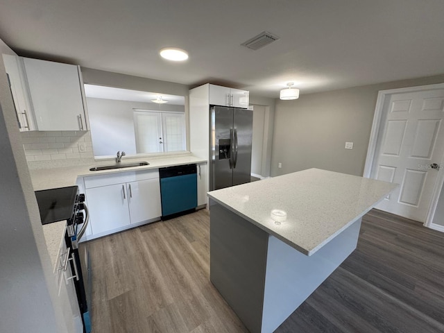 kitchen with a kitchen island, visible vents, appliances with stainless steel finishes, wood finished floors, and a sink
