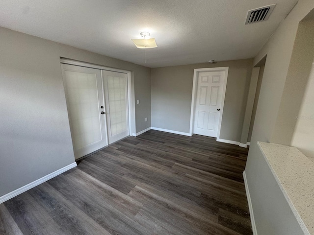 unfurnished bedroom with visible vents, dark wood-style flooring, baseboards, and a closet
