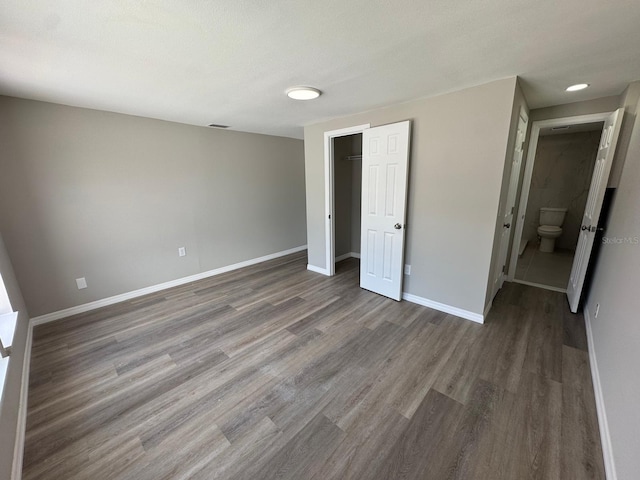 unfurnished bedroom featuring baseboards, wood finished floors, and a closet