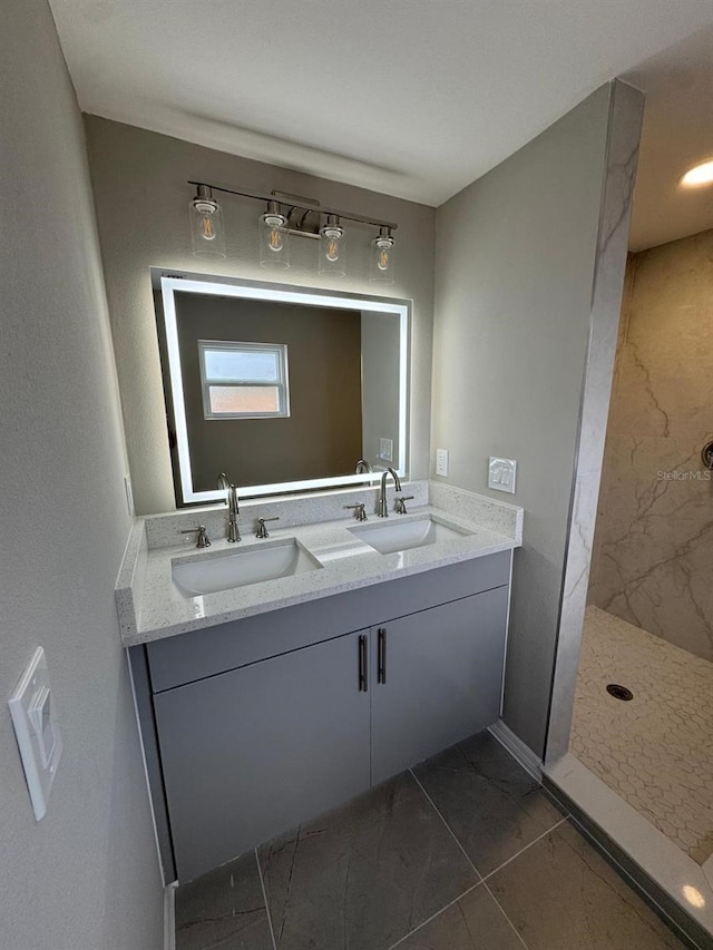 bathroom featuring double vanity, a sink, a walk in shower, and baseboards