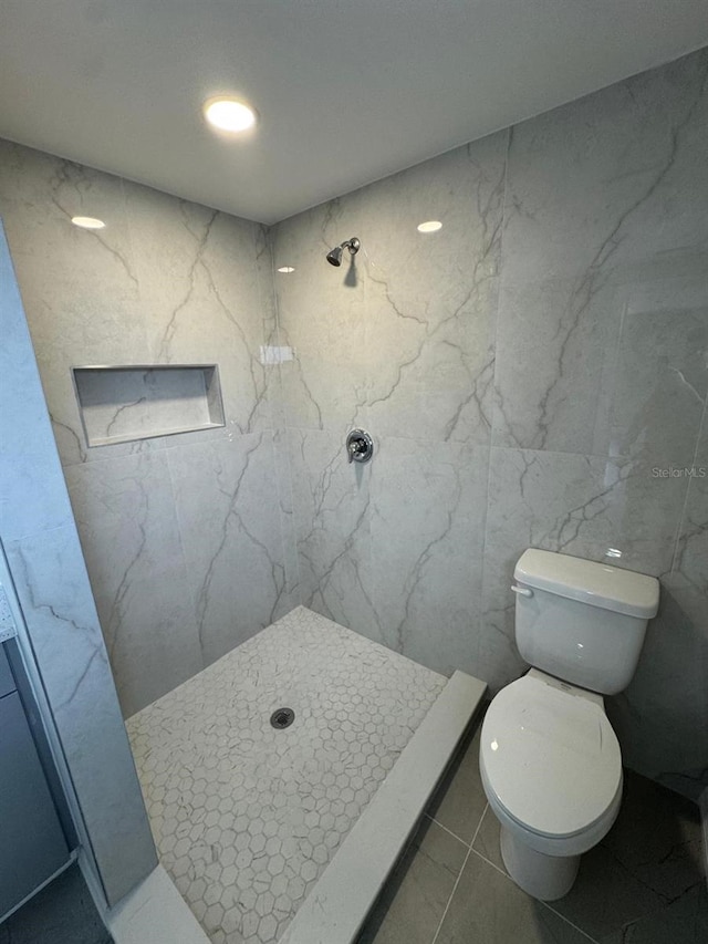 bathroom featuring tile walls, a shower stall, toilet, and marble finish floor