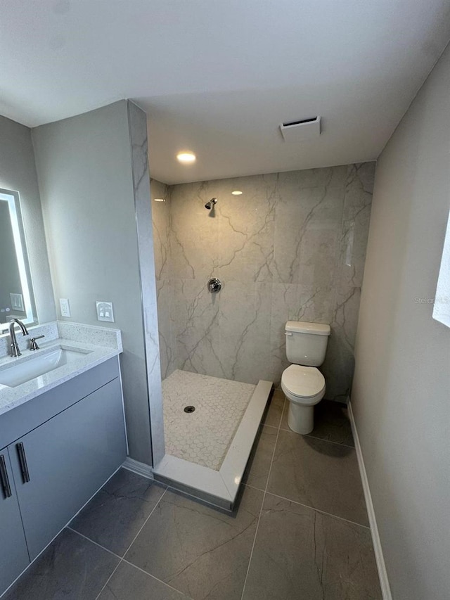 bathroom with toilet, a marble finish shower, marble finish floor, and vanity