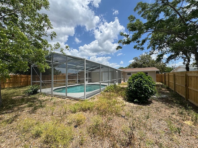 view of swimming pool with glass enclosure, a fenced in pool, and a fenced backyard