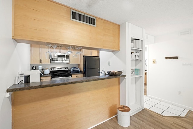 13512 Palmwood Ln Unit 13512, Tampa, FL 33618 - kitchen featuring a peninsula, light brown cabinetry, visible vents, appliances with stainless steel finishes, and wood finished floors