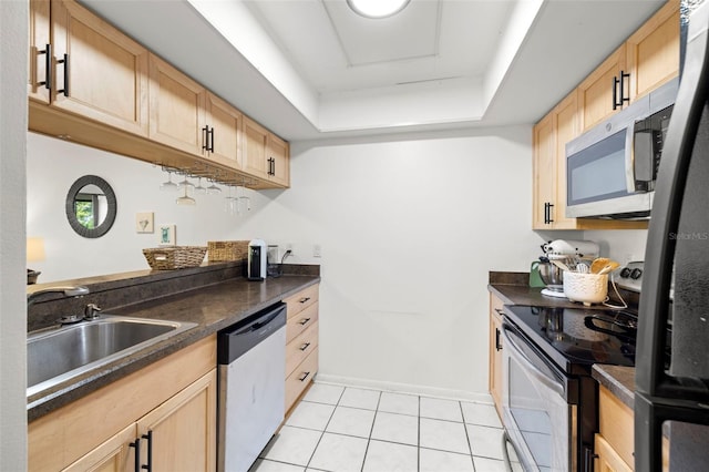 13512 Palmwood Ln Unit 13512, Tampa, FL 33618 - kitchen with dark countertops, a raised ceiling, stainless steel appliances, a sink, and light brown cabinetry