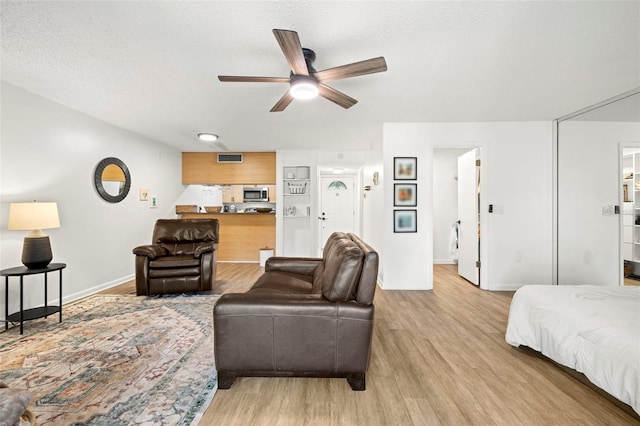 13512 Palmwood Ln Unit 13512, Tampa, FL 33618 - living room featuring light wood-type flooring, baseboards, a ceiling fan, and a textured ceiling