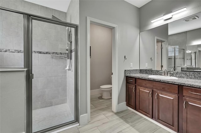 bathroom featuring vanity, baseboards, a stall shower, toilet, and visible vents