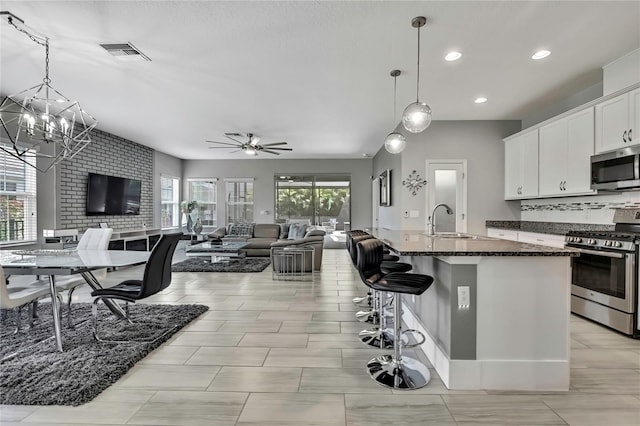 kitchen with tasteful backsplash, visible vents, a sink, open floor plan, and stainless steel appliances