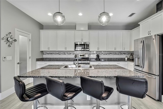 kitchen with tasteful backsplash, visible vents, white cabinetry, and stainless steel appliances