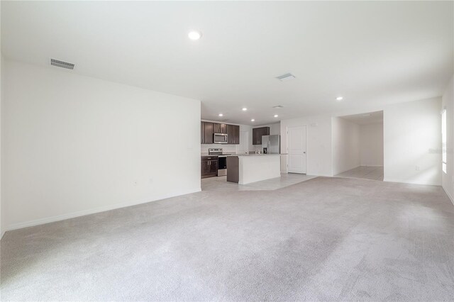 unfurnished living room with recessed lighting, visible vents, light colored carpet, and baseboards