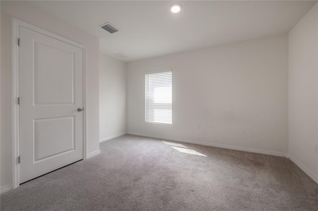 carpeted empty room with visible vents and baseboards